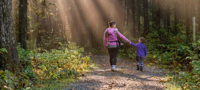 Una mujer y un niño caminan por un bosque en British Columbia Ridge, Canadá.
