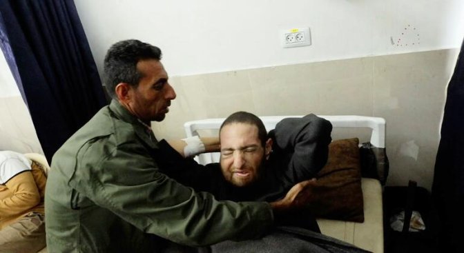 Raed Abu Warda, un hombre con una chaqueta verde, consuela a su hermano Hamid Abu Warda, un paciente de cáncer, en el Hospital Al-Shifa de la ciudad de Gaza.