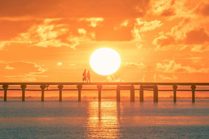 Una pareja camina por un muelle de madera al atardecer en las Maldivas.